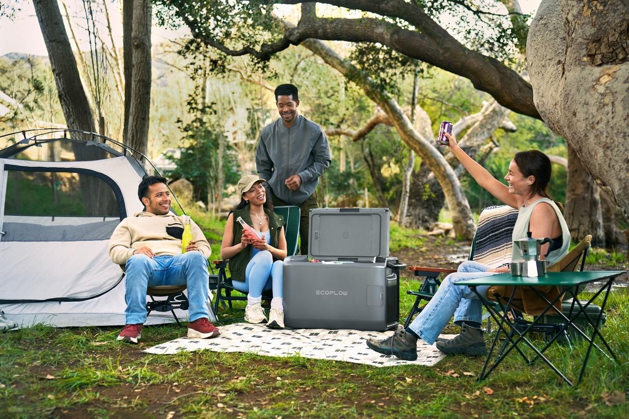Freunde campen mit Powerstation und stoßen an.
